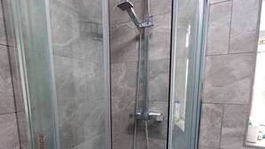 A glass-enclosed shower stall with a handheld showerhead and a wall-mounted faucet. - Room-single Cosy Room Near CBS Arena and (Coventry)
