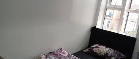 A bedroom with a bed, a window, and a wardrobe.