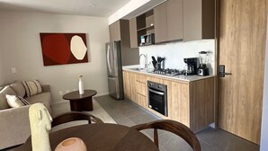 Una cocina moderna con armarios de madera, horno empotrado y comedor con mesa y sillas.