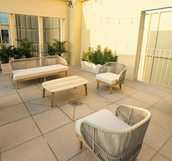 Une terrasse extérieure aménagée avec des meubles en osier, notamment des canapés et des fauteuils, ainsi que des plantes en pot.