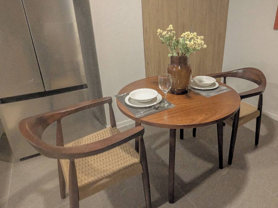 Una mesa de comedor con cuatro sillas, un jarrón con flores y una botella.