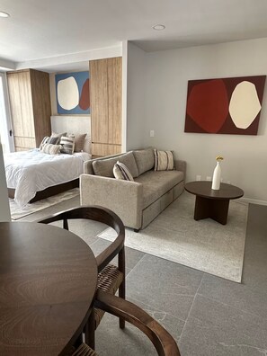 A modern bedroom with a bed, a sofa, a dining table, and a small side table. - Centro Zapopan N50 (Zapopan)