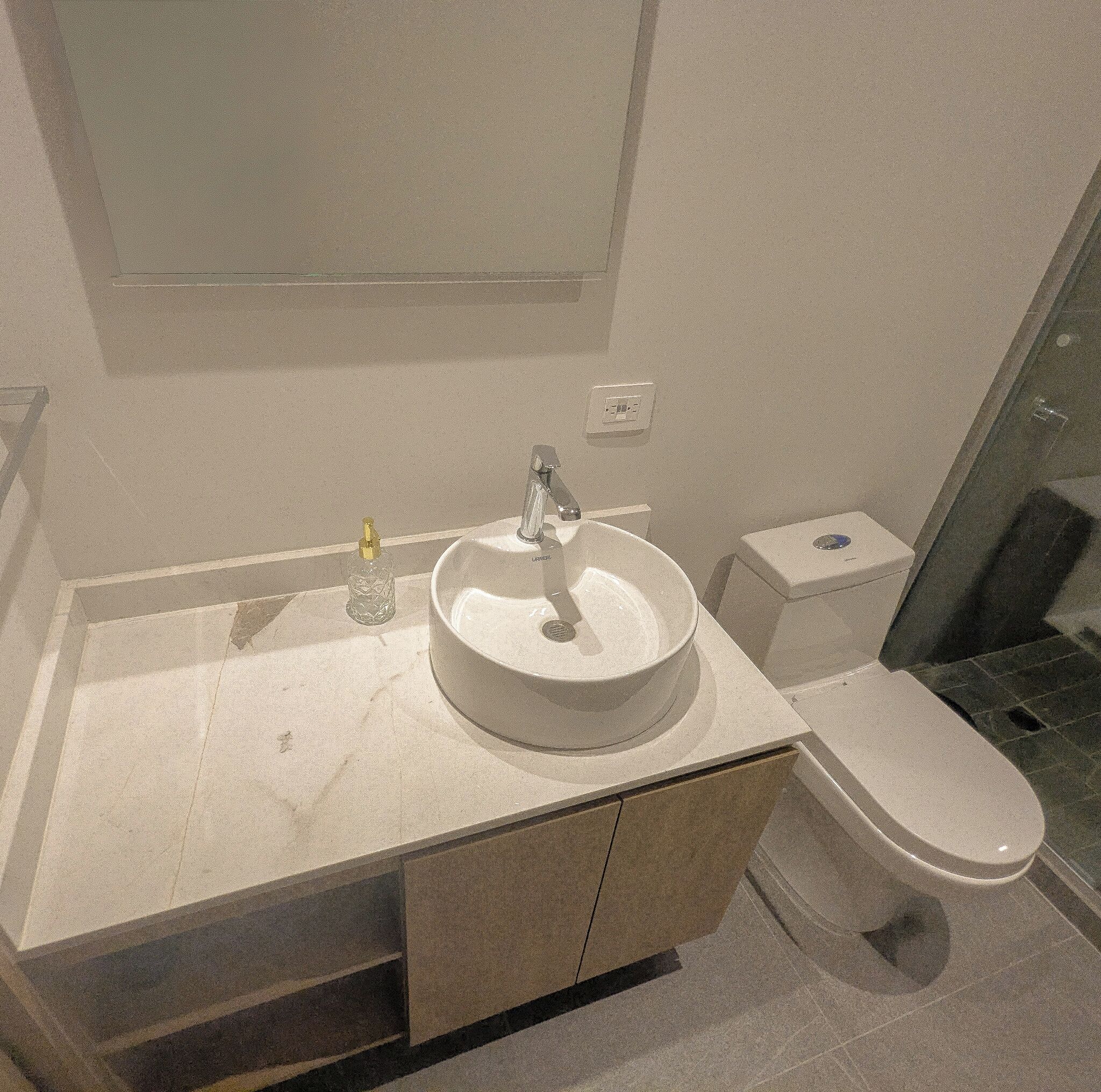 Un baño con lavamanos, inodoro y espejo.