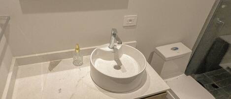 Un baño con lavamanos, inodoro y espejo.