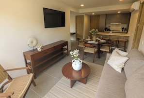 A living room with a sofa, a coffee table, a TV, a dining area with chairs and a table, and a kitchen in the background. - Centro Zapopan N50 (Zapopan)