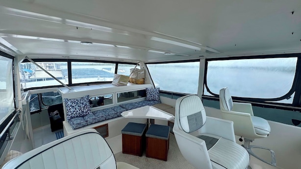 A boat interior with a dining area, seating, and a view of the water. - Reel Excuse - Yacht Living (Fort Myers Beach)