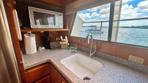 A compact galley with a microwave, sink, and window overlooking water. - Reel Excuse - Yacht Living (Fort Myers Beach)