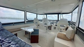 A boat interior with seating, a table, and a steering wheel.