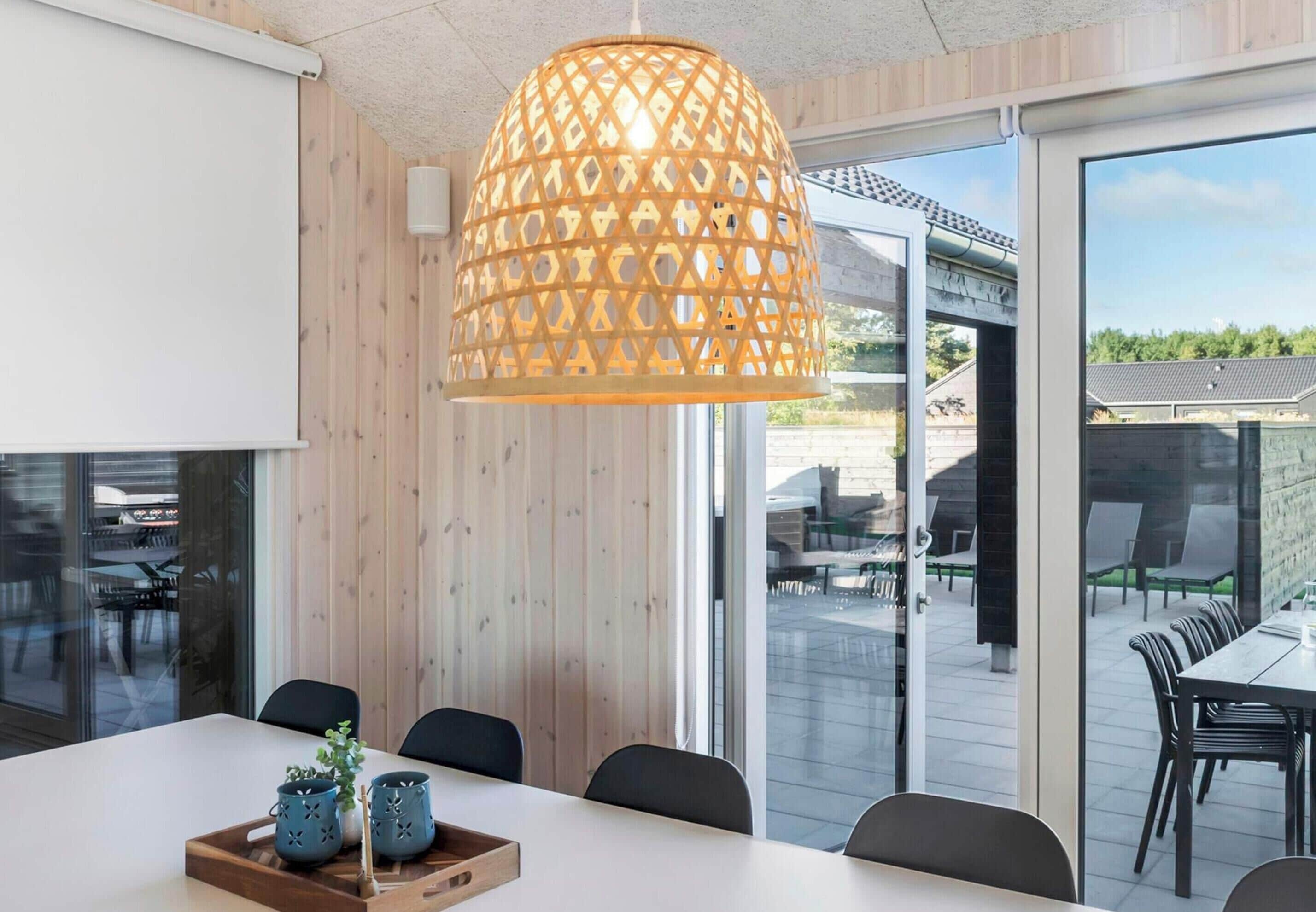 A modern dining area with a white table, black chairs, and a decorative hanging light fixture.