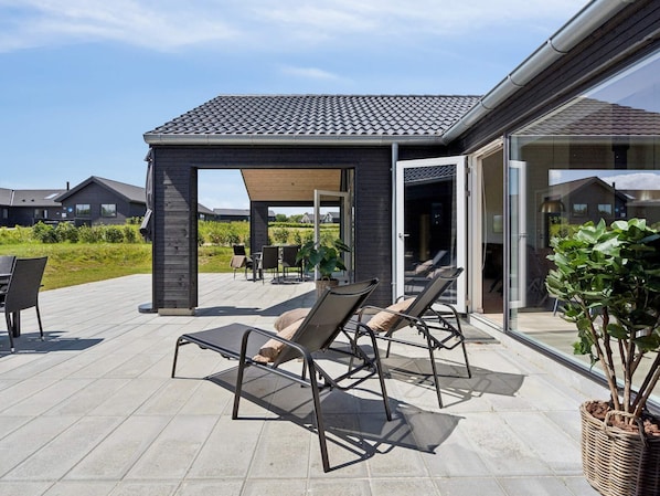 Un patio techado al aire libre con sillones de descanso y una pérgola.
