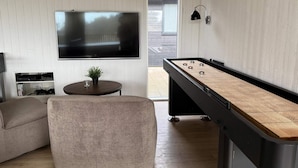 A modern living room with a foosball table, a flat-screen TV, a sofa, and a small table with a plant. - 5 Star Holiday Home in Idestrup (Idestrup)