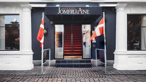 La entrada del Hotel Jomeroane, con alfombra roja, dos banderas y un toldo negro.