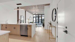 A modern kitchen with a dishwasher, wooden cabinets, and a large island. - Sleek NoLibs 1BR Close to Hotspots | Sleeps 4 (Philadelphia)