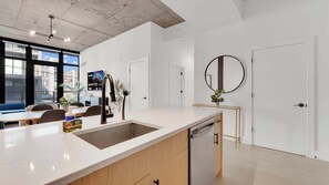 A modern kitchen with a large island, a built-in dishwasher, and a dining area with seating. - Sleek NoLibs 1BR Close to Hotspots | Sleeps 4 (Philadelphia)