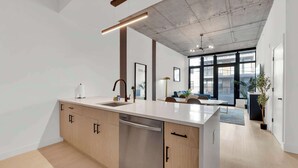 A modern kitchen with a large island, built-in appliances, and a view to a living area with a sofa and a coffee table. - Sleek NoLibs 1BR Close to Hotspots | Sleeps 4 (Philadelphia)