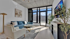 A modern living room with a sofa, coffee table, and a TV mounted on the wall. - Trendy NoLibs 1BR Near City Spots | Sleeps 4 (Philadelphia)