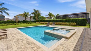 A rectangular swimming pool with a hot tub, surrounded by a brick patio. - Comfort 6BR Getaway, Private Pool, Great Location (Kissimmee)