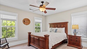 Ein Schlafzimmer mit einem hölzernen Bett, einem Nachttisch, einem Stuhl und einem Deckenventilator.