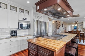 A modern kitchen with white cabinetry, stainless steel appliances, and a wooden island. - Waterfront Retreat w/ Private Pool, Dock, Theater Room & Boat Access (Cape Carteret)