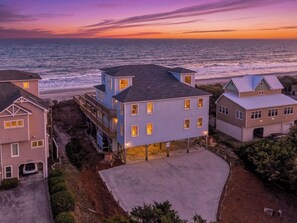 A coastal residential area with houses, a concrete driveway, and a view of the ocean at sunset. - Thalasea, Oceanfront House in Emerald Isle, NC! (Emerald Isle)