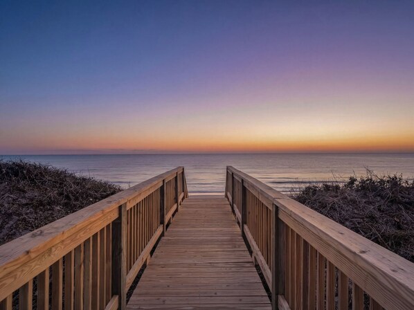 A wooden boardwalk leading to a beach with a clear view of the ocean and a sunset in the background. - Thalasea, Oceanfront House in Emerald Isle, NC! (Emerald Isle)