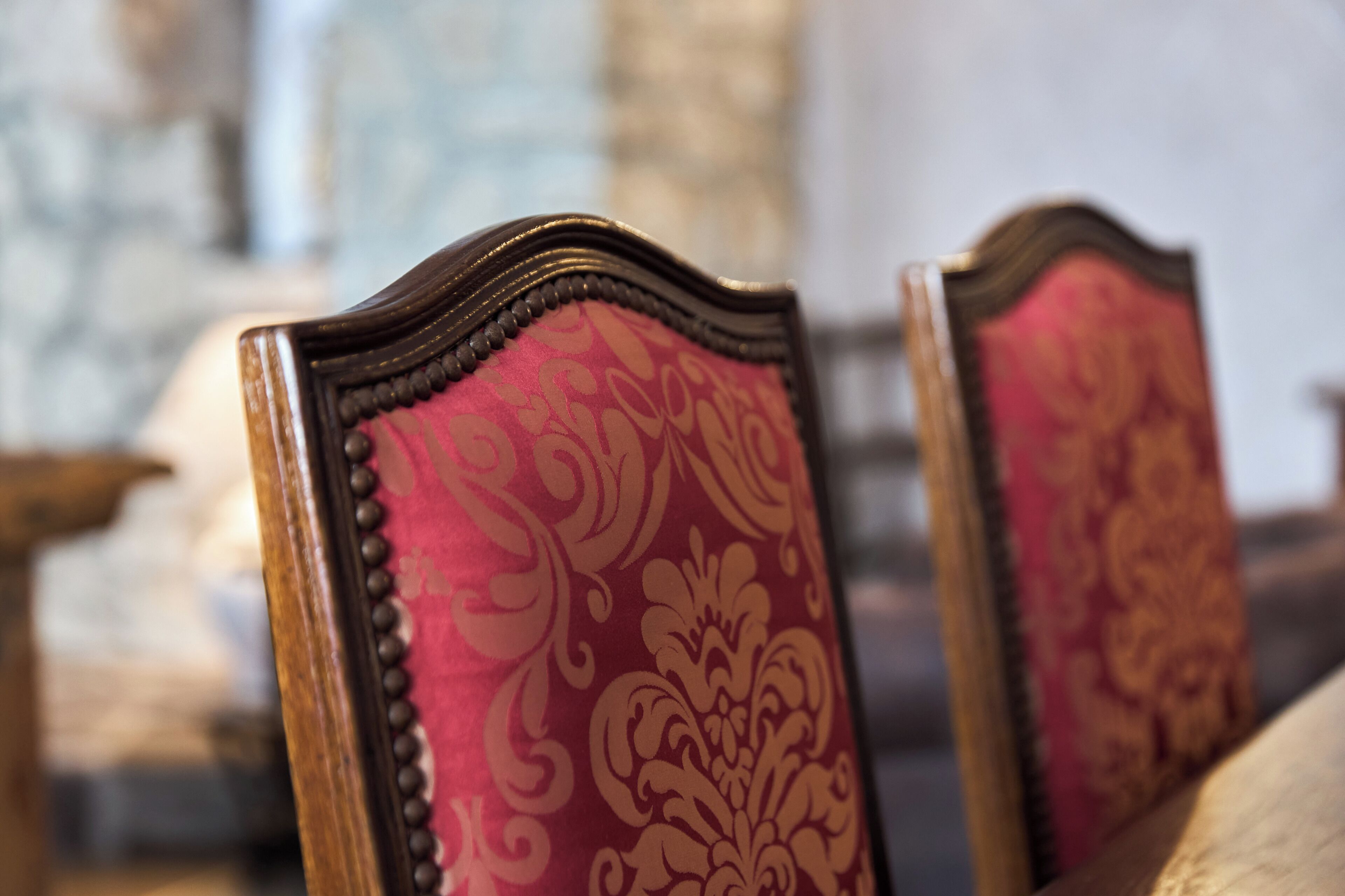 A close-up of a chair with a patterned fabric and wooden frame.