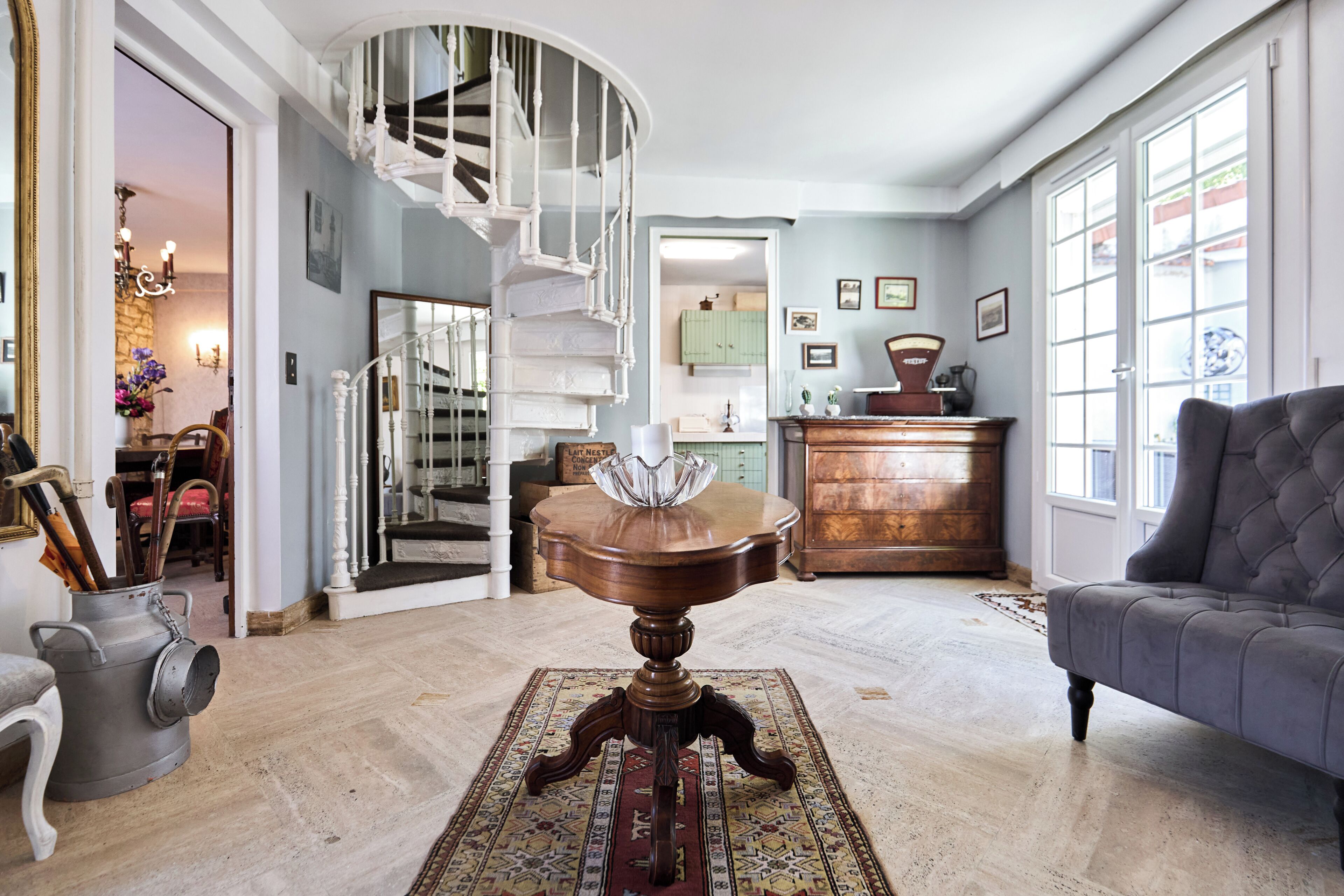 A spacious living room with a grand staircase, a comfortable sofa, and a dining area.