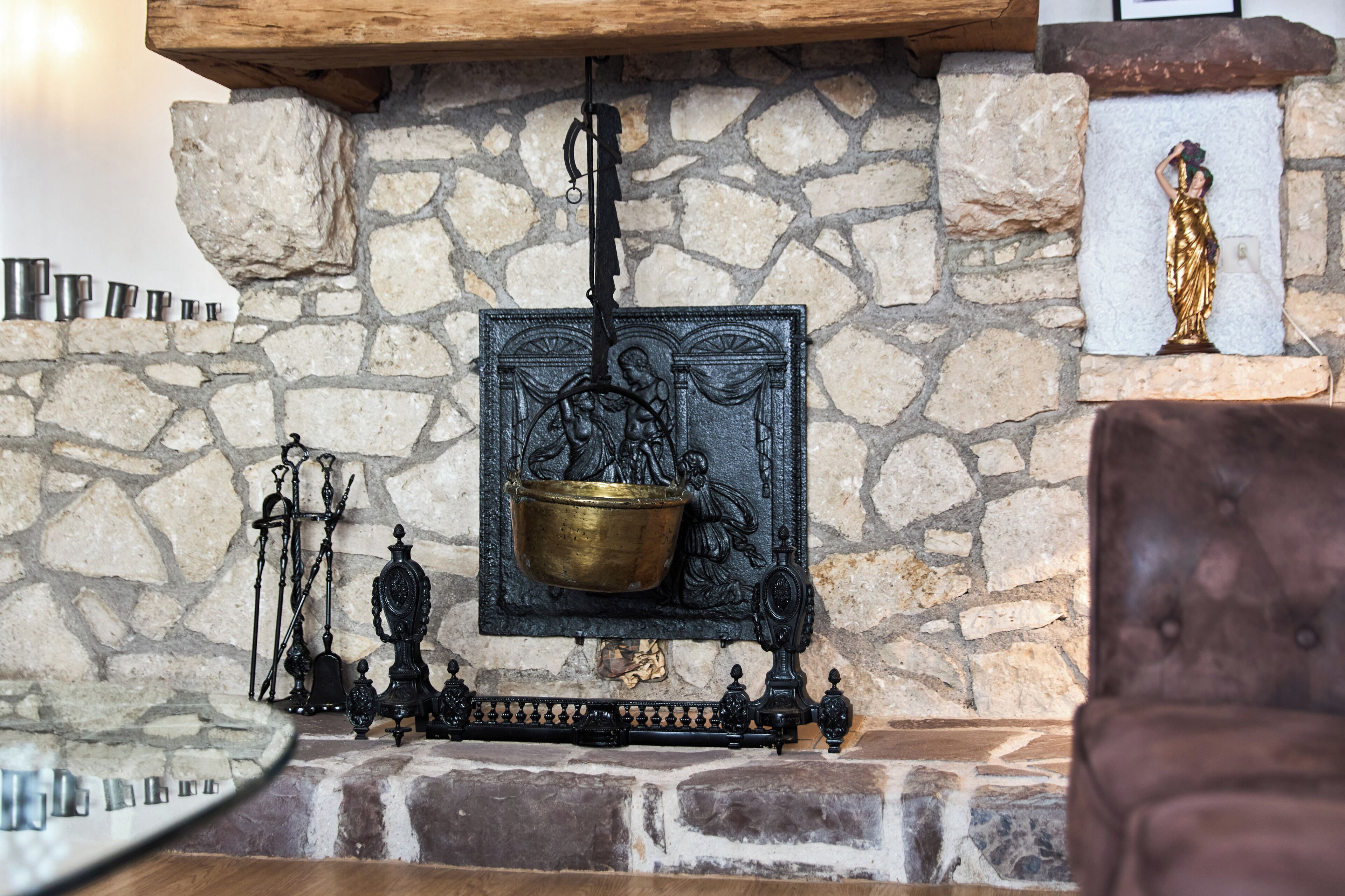 A stone fireplace with a brass pot, a statue, and a decorative metal piece.