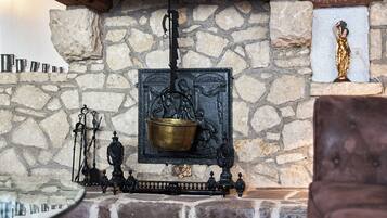 A stone fireplace with a brass pot, a statue, and a decorative metal piece.