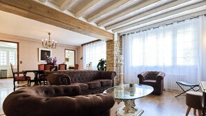 A spacious living room with a brown sofa, a glass coffee table, and a stone accent wall.