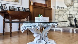 A dining table with a glass top and ornate white legs, set on a wooden floor.
