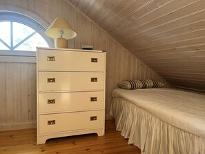A bedroom with a wooden ceiling, a dresser with drawers, a bed with a striped pillow, and a window with a view. - 5 Star Holiday Home in Ingaro (Ingaro)