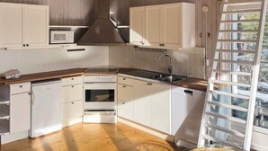 A kitchen with white cabinets, a microwave, a stove, and a dishwasher. - 5 Star Holiday Home in Ingaro (Ingaro)
