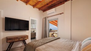 Ein Schlafzimmer mit einem Bett, einem an der Wand befestigten Fernseher, einer hölzernen Kommode und einem Fenster mit Blick.