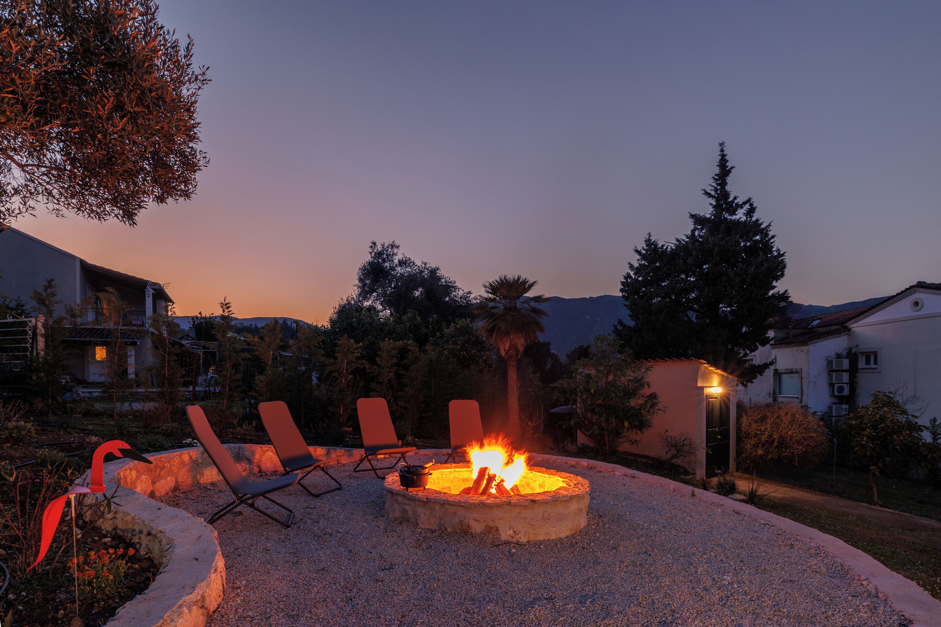 Un foyer extérieur avec des fauteuils confortables, un foyer en pierre et une vue sur le paysage environnant.