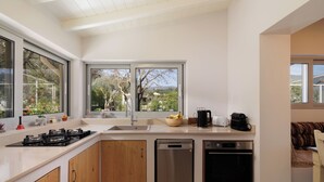 Eine moderne Küche mit großem Fenster, integrierten Geräten und Blick ins Freie.
