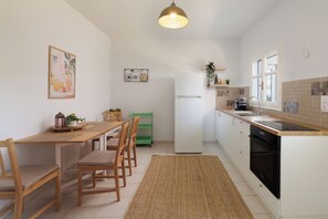 Una cocina con una mesa de comedor, sillas, un refrigerador, un lavamanos y una ventana.