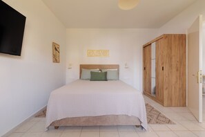 Un dormitorio con cama, televisor de pantalla plana, armario de madera y una pequeña alfombra.