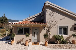 A house with a tiled roof, a front door, and potted plants. - Charming sea view private villa in Kato Korakiana, Corfu, 
quiet green area . (Kato Korakiana)