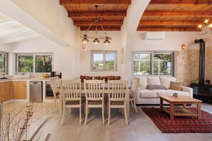 A modern kitchen with wooden cabinets, a dining table with chairs, a sofa, and a fireplace. - Charming sea view private villa in Kato Korakiana, Corfu, 
quiet green area . (Kato Korakiana)