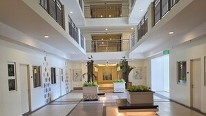 Eine großzügige Hotelhalle mit hoher Decke, mehreren Etagen und einem offenen Innenbereich mit Blumentöpfen.