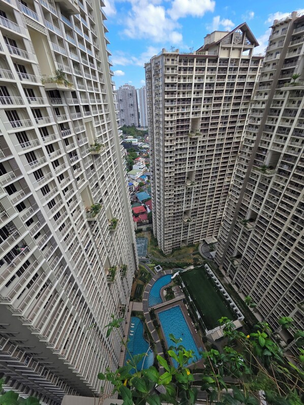 A high-rise residential building with balconies, a swimming pool, and a landscaped area.