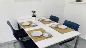 A dining table set with plates, cups, and cutlery, surrounded by chairs. - Ferienwohnung in Petersdorf auf Fehmarn (Petersdorf)