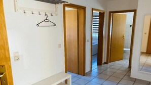 A hallway with wooden doors, a coat rack, and a bench. - Ferienwohnung in Petersdorf auf Fehmarn (Petersdorf)