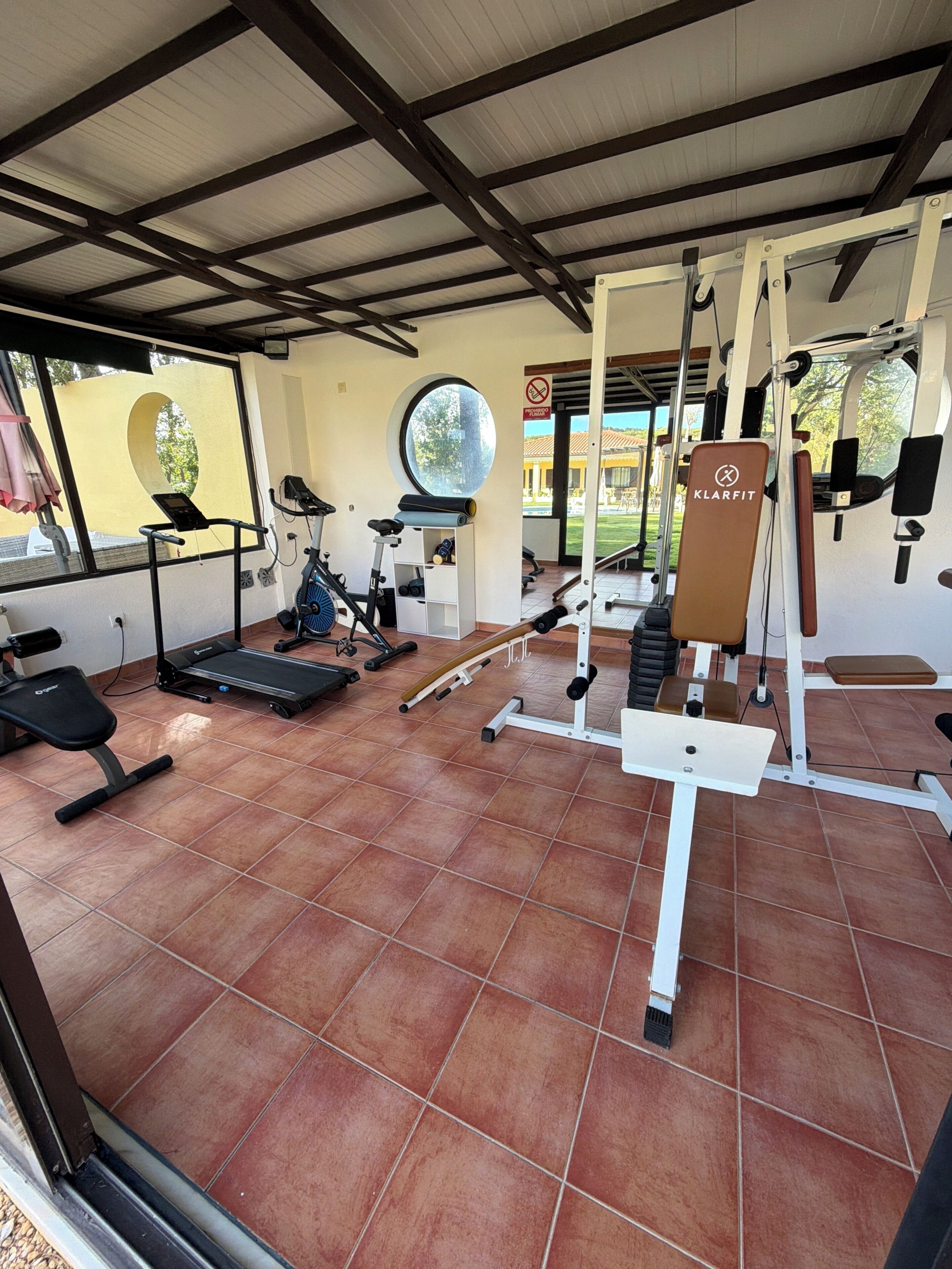 A gym with exercise equipment, a treadmill, and a bench.