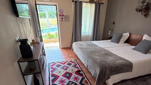 Un dormitorio con cama, escritorio, silla, alfombra y vistas al exterior.