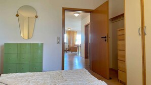 Une chambre à coucher avec un lit, une tête de lit verte, une armoire en bois et un miroir au mur.