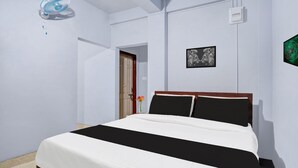 A bedroom with a bed, a wall-mounted fan, a door, and a framed picture.
