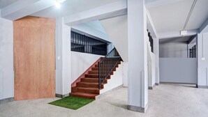 A modern interior with a staircase, white walls, and a wooden door.