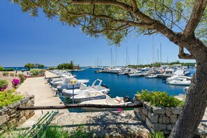 A marina with boats docked, a stone wall, and a tree. - Villa in Sardinia Near Porto Ottiolu Beach (Budoni)